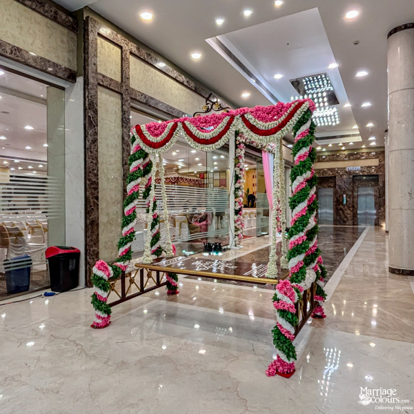 Wedding decor featuring a traditional brass swing heavily decorated with pink, green, and white flowers.