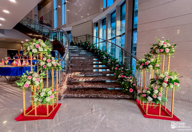 Marble staircase decorated with lush pink and white floral arrangements for a wedding entry.