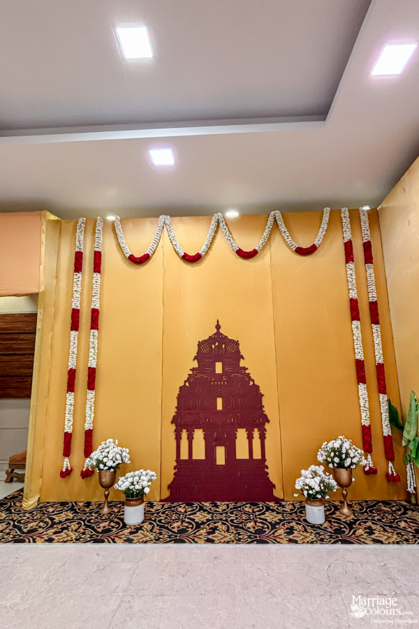 Simple golden backdrop adorned with a temple silhouette cutout and long flower garlands.