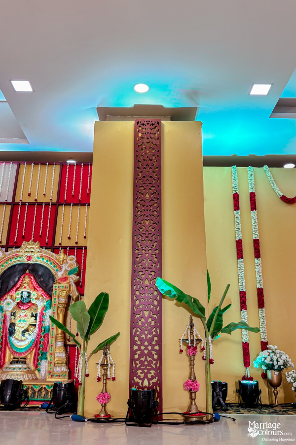 Traditional wedding decor featuring banana trees, a dark column, and a colorful deity idol.