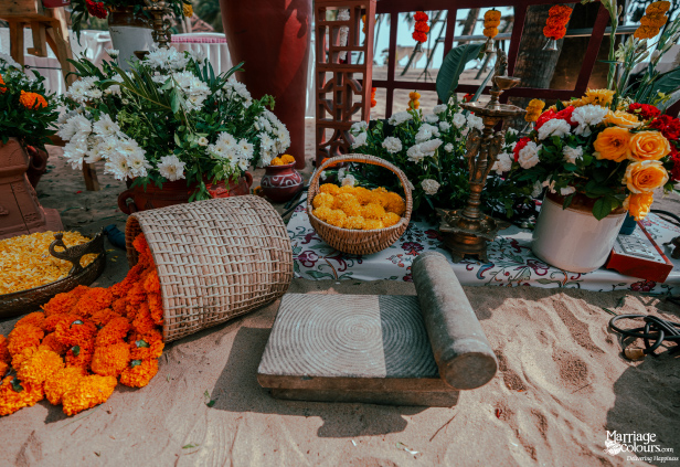 Traditional grinding stone and marigold flowers spilling from a basket for a ceremony on the sand.