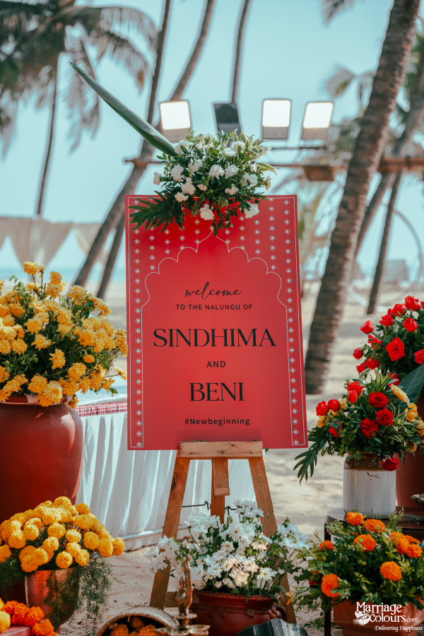 Red welcome sign for the Nalungu of Sindhima and Beni, surrounded by colorful marigold flowers on the beach