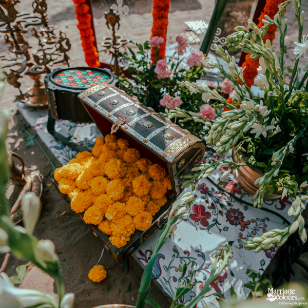 Rustic wooden chest overflowing with bright yellow marigold flowers, surrounded by white florals.