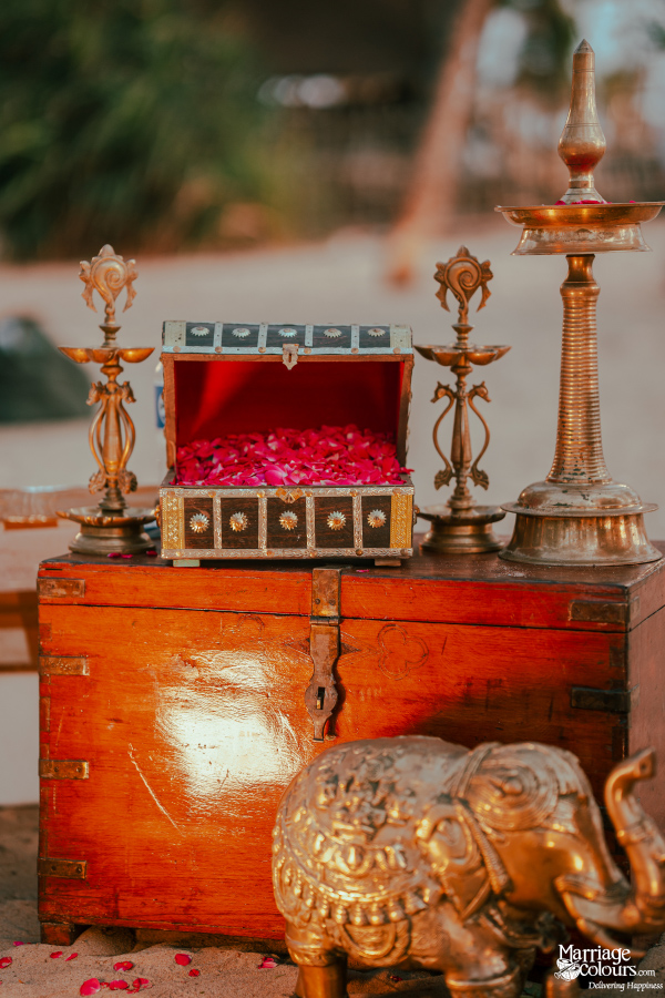 Traditional wood chests, brass lamps, and a golden elephant statue on the beach sand.