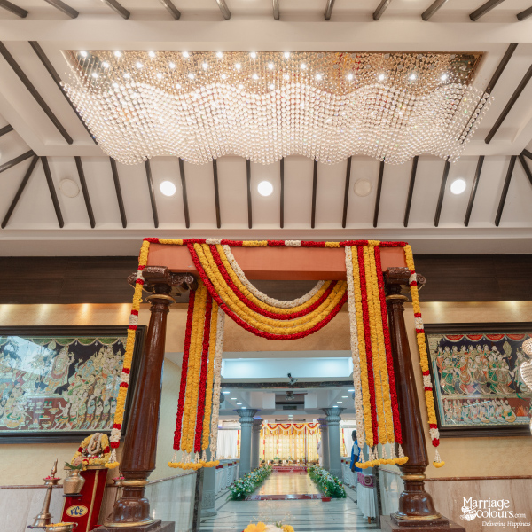 Opulent hall interior with a large crystal chandelier and traditional archway of red and yellow flowers.