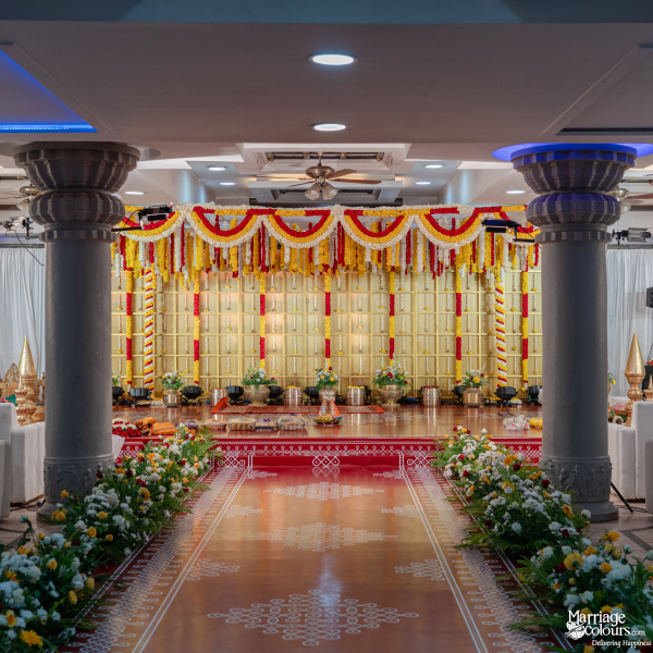 Symmetrical view of a vibrant traditional Indian wedding stage with gold backdrop and columns.