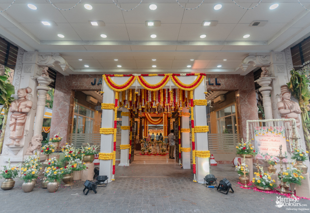 Wide shot of a decorated Indian wedding hall entrance framed by stone sculptures.