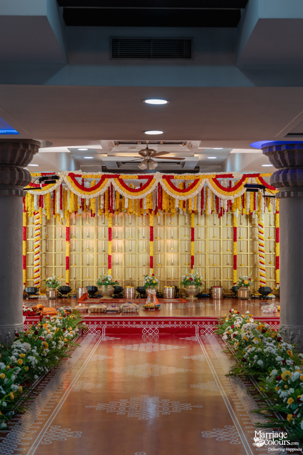 Opulent Indian wedding stage decor with a gold backdrop, flower garlands, and a floral aisle.