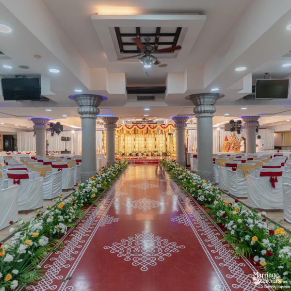 Long wedding aisle with a red carpet, floral borders, and traditional Kolam designs.