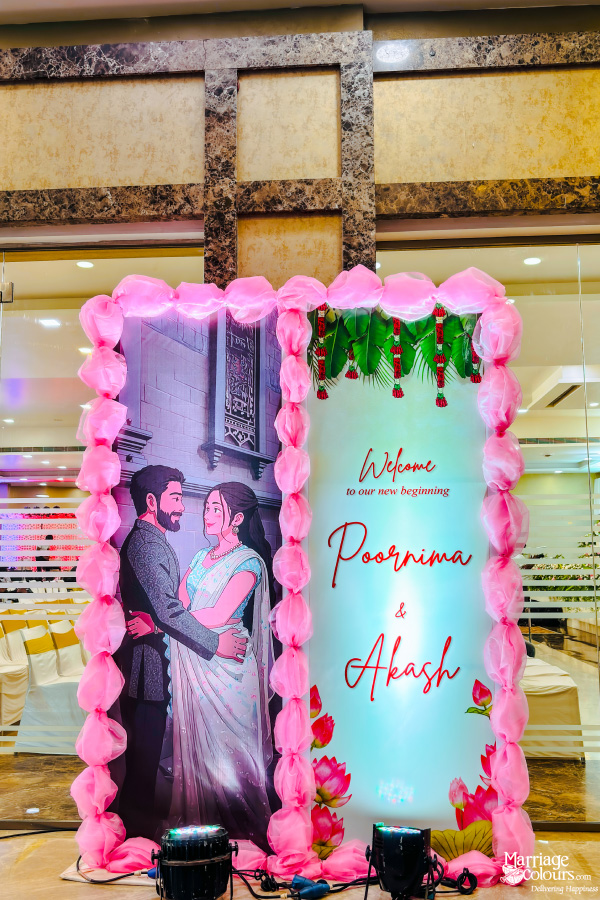 A large welcome sign for a wedding reception, featuring a custom illustration of the couple, Poornima and Akash, and a border of pink fabric.
