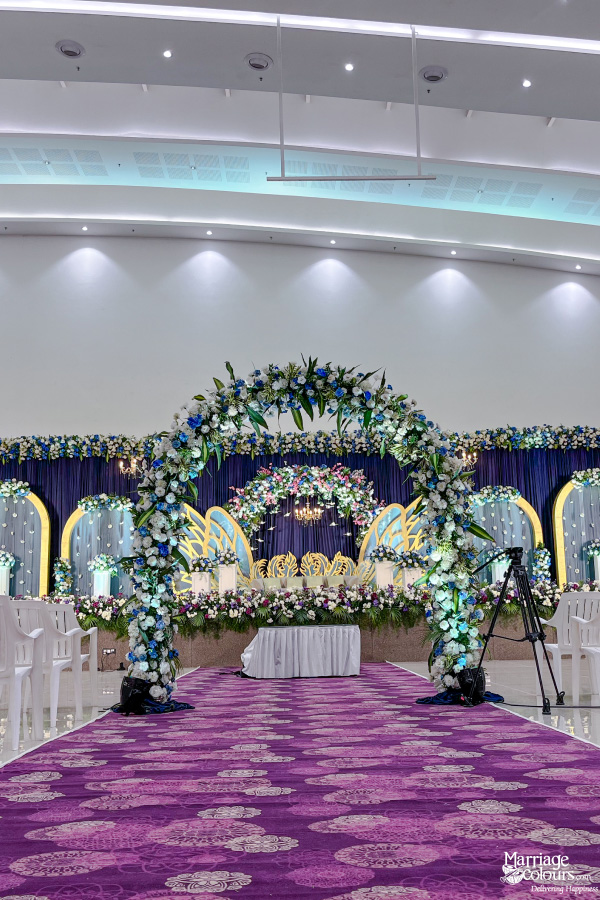 Grand indoor wedding stage with a floral arch, royal blue backdrop, and elaborate swan motif decor.