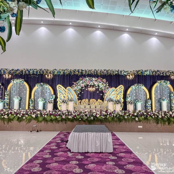 Grand wedding stage with a blue backdrop, white swan motifs, and abundant blue and white flowers.