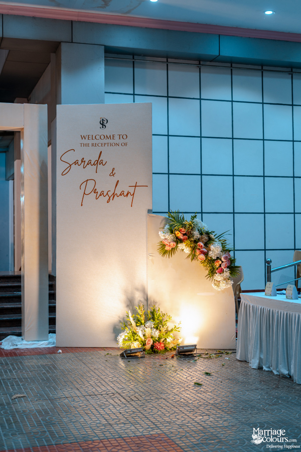 Minimalist welcome sign for the reception of Sarada and Prashant, framed by flowers