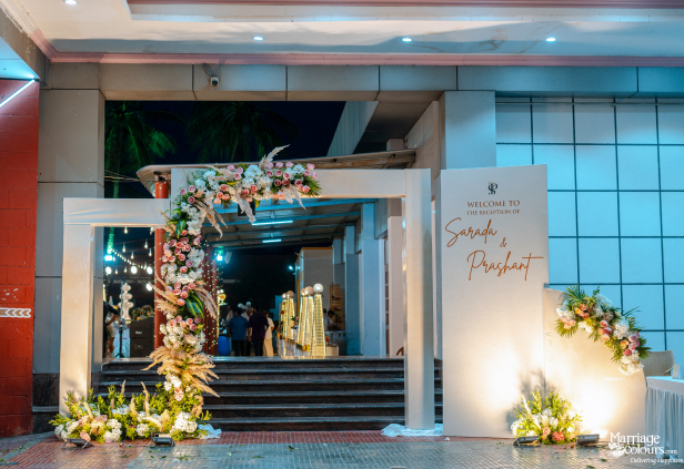 Reception welcome area with a white sign for Sarada and Prashant and a rustic floral archway.