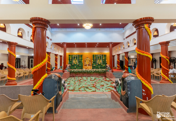 Grand traditional hall with elephant statues framing a lotus pond and a Hindu-themed stage with a Ganesha idol.