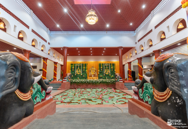 Grand hall with elephant statues framing a lotus pond and a Hindu-themed stage with a Ganesha idol.