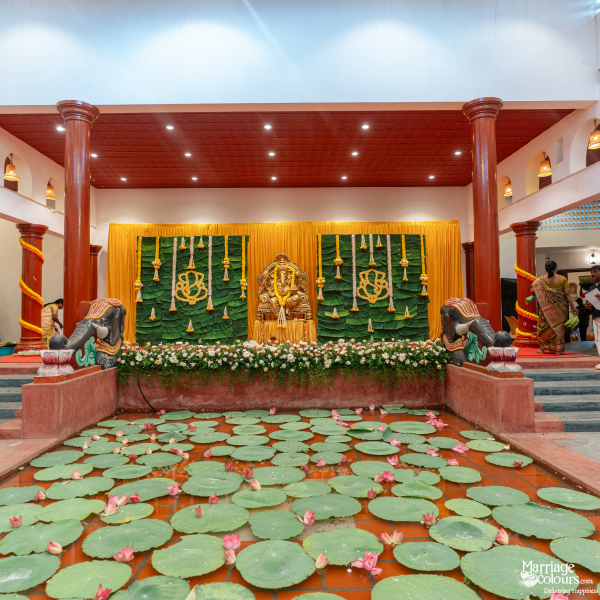 Grand hall with elephant statues framing a lotus pond and a Hindu-themed stage with a Ganesha idol.