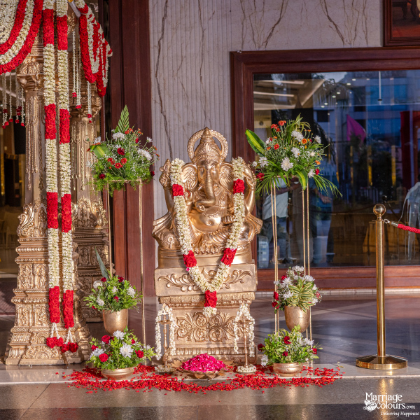 Golden Ganesha statue decorated with garlands and flowers, set up in a traditional wedding entrance.