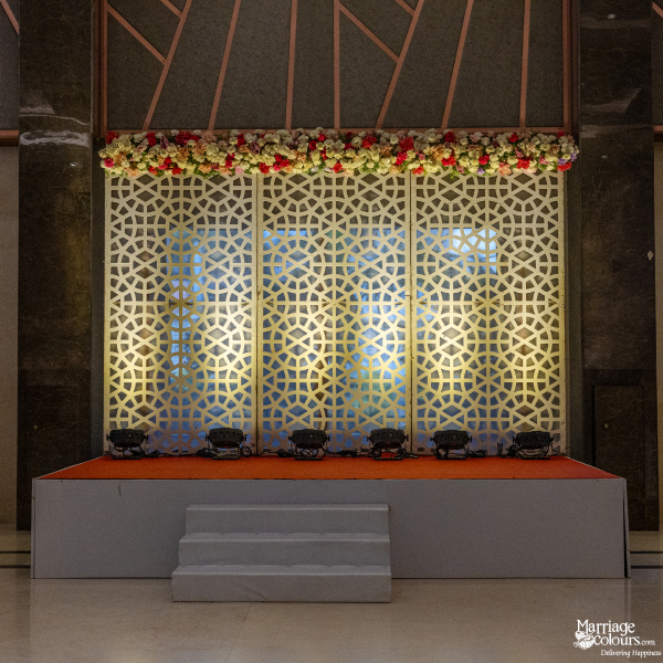 Modern stage with a white geometric lattice backdrop, overhead floral arrangement, and white stairs.