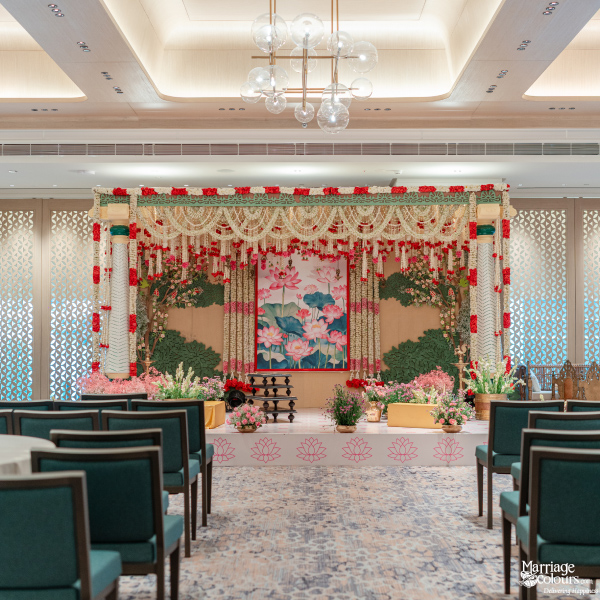Elegant wedding stage with a lotus backdrop, floral garlands, and dark teal guest seating.