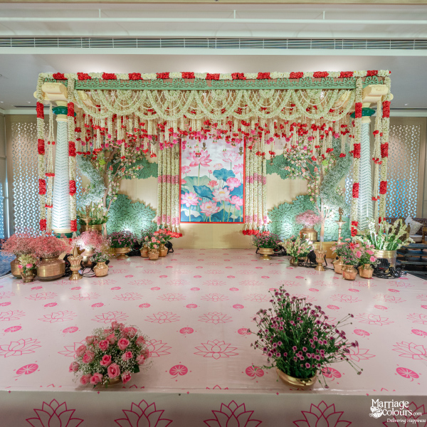 Pink-themed wedding stage with a lotus patterned floor and lush white and red garlands