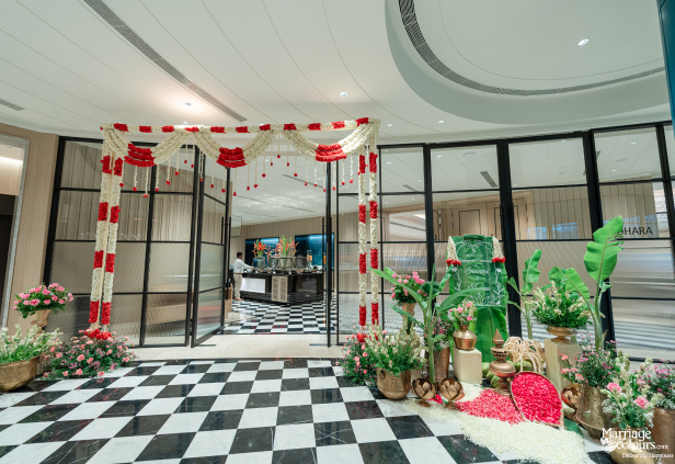 Checkered floor hallway with red and white floral arch leading to an engagement ceremony area.
