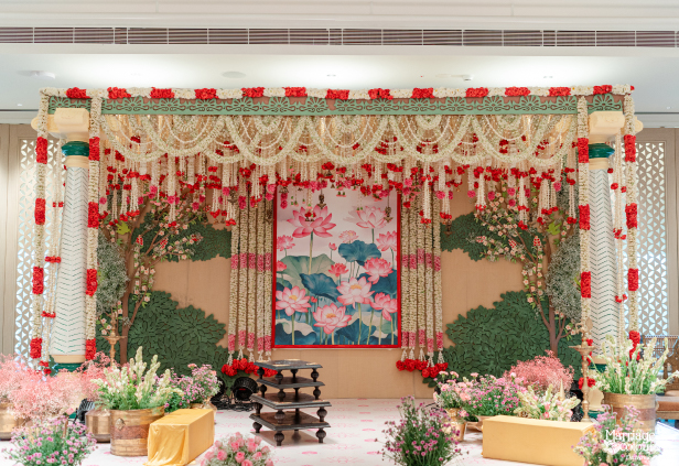 Elaborate pink and green wedding stage with a lotus artwork backdrop and abundant fresh flowers