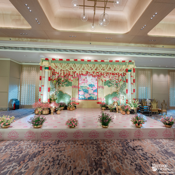 Elegant indoor wedding stage with lotus motif, pink floor runner, and luxurious floral decor.