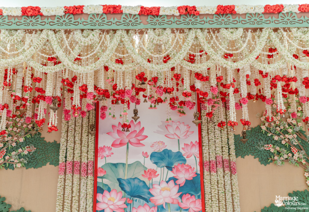 Close-up of a wedding stage canopy with lush white, red, and pink floral garland hangings.