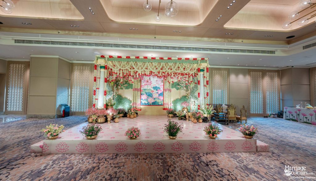 Elegant indoor wedding reception stage with a lotus theme and soft pastel floral decor.