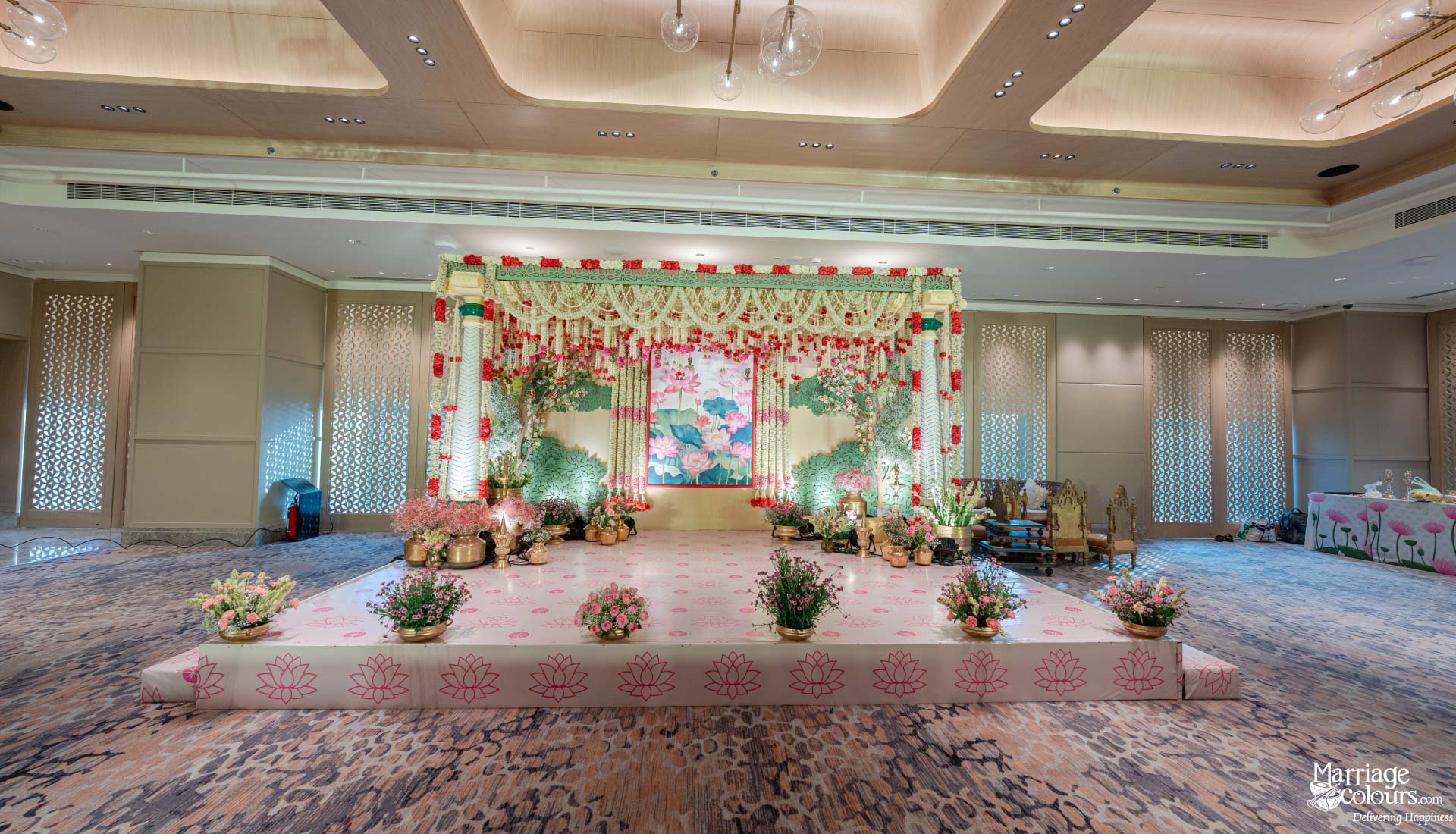 Elegant indoor wedding reception stage with a lotus theme and soft pastel floral decor.