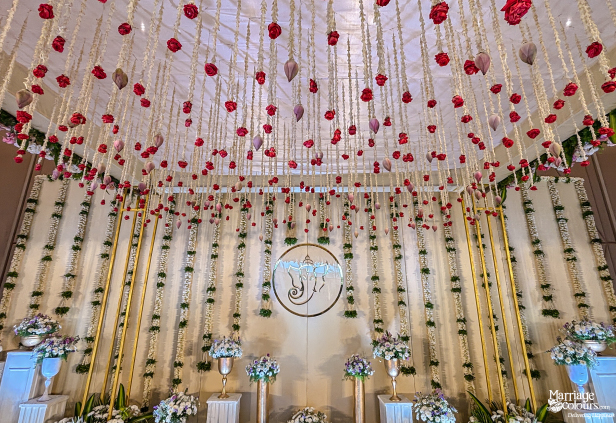 Dramatic wedding stage and ceiling featuring cascading floral strings, gold pillars, and an illuminated Ganesha centerpiece.