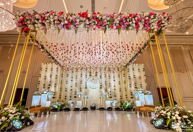 Wedding stage with a magnificent flower canopy, golden pillars, and traditional ceremony seating.