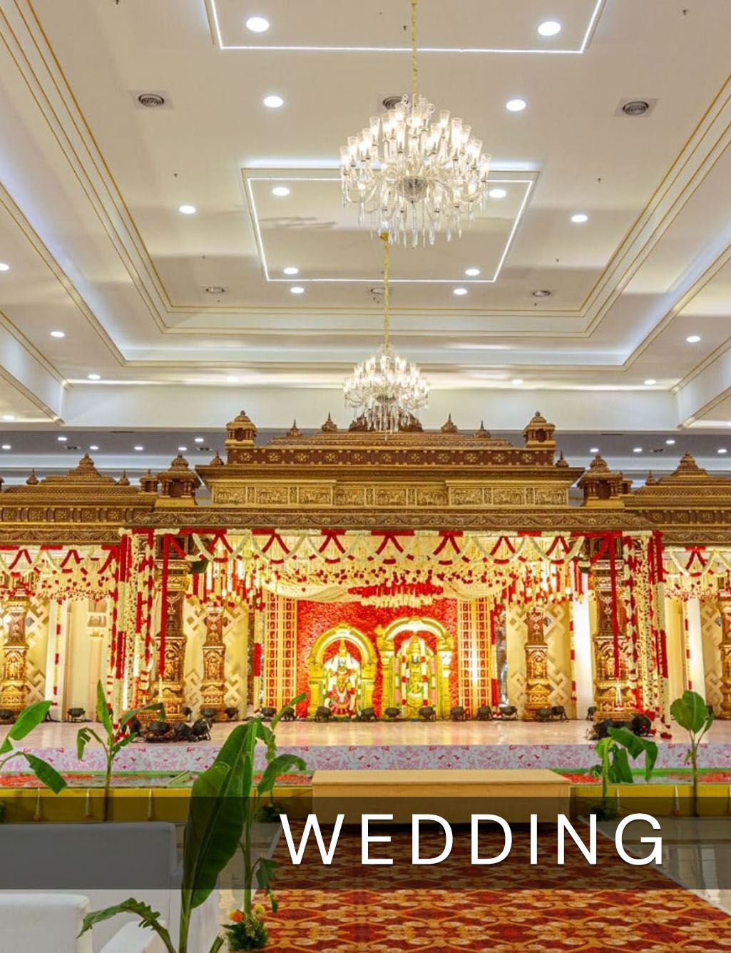 Luxurious indoor wedding stage with a grand gold temple theme and two elegant crystal chandeliers.