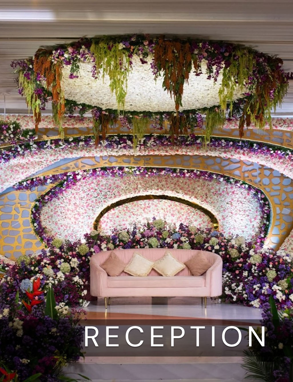 Unique floral backdrop with gold concentric rings, a white hanging centerpiece, and a small pink reception sofa.
