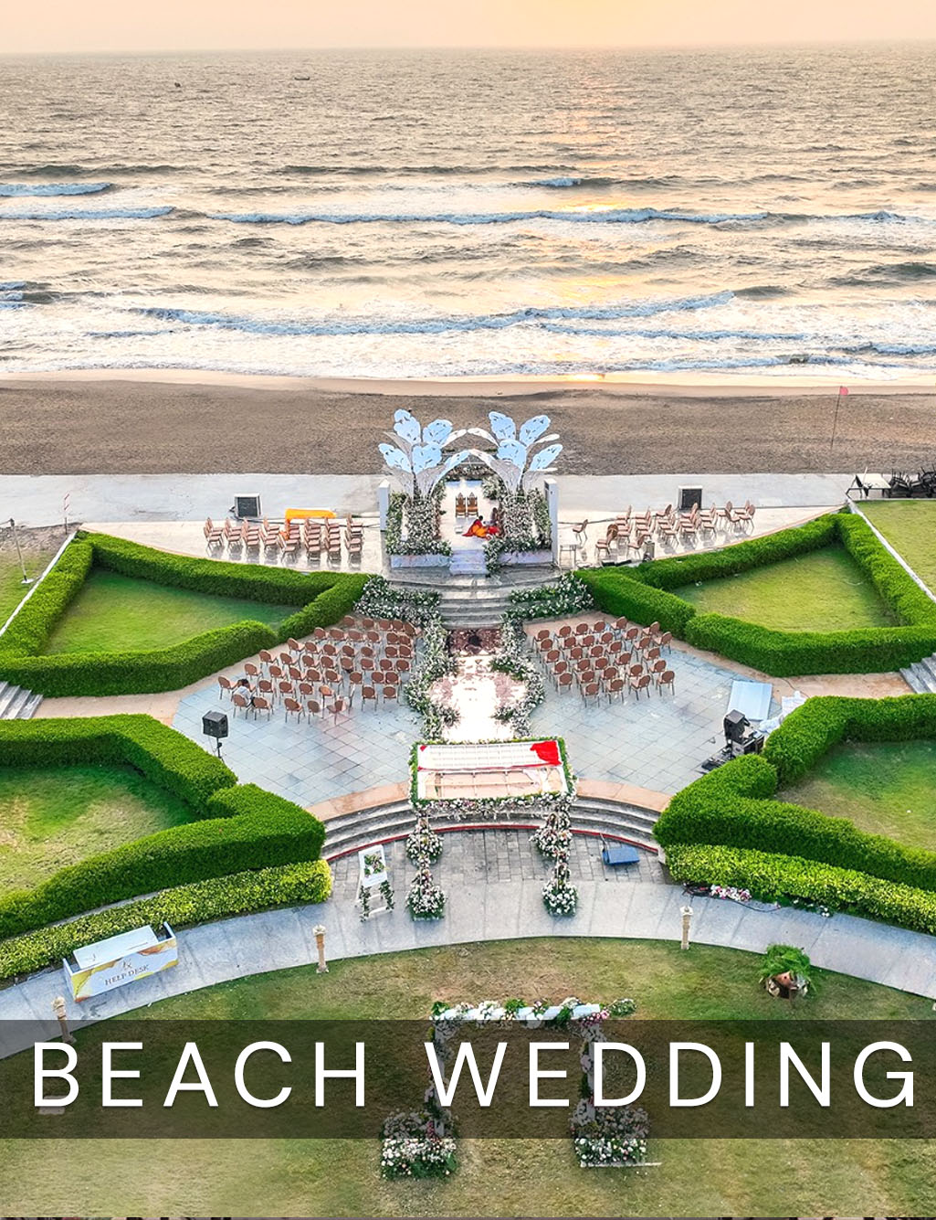 Aerial view of a sprawling beachfront wedding venue with tiered seating, hedgerows, and ocean waves crashing