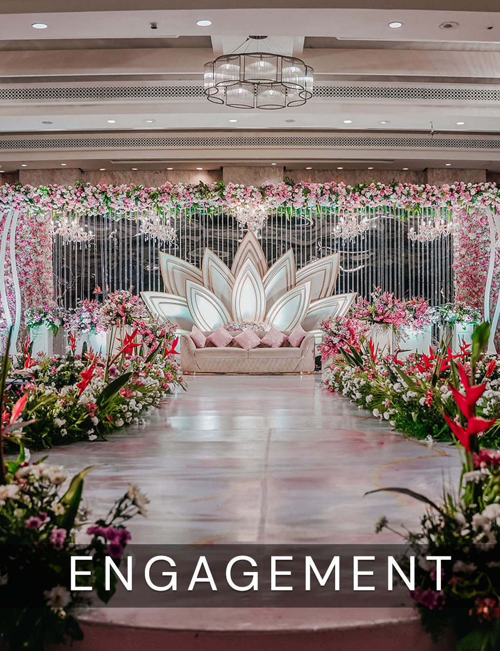 Modern stage decor showcases an illuminated lotus-shaped sofa, elegant chandeliers, and a beautifully flower-lined aisle leading up.