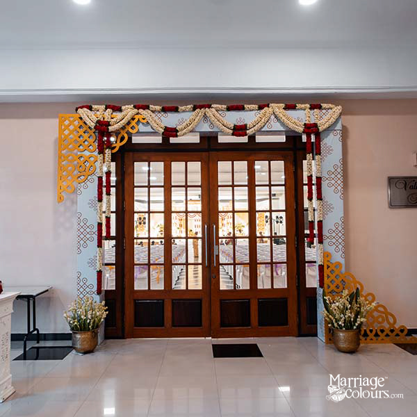 Wedding entrance with wooden double doors framed by floral garlands and golden lattice