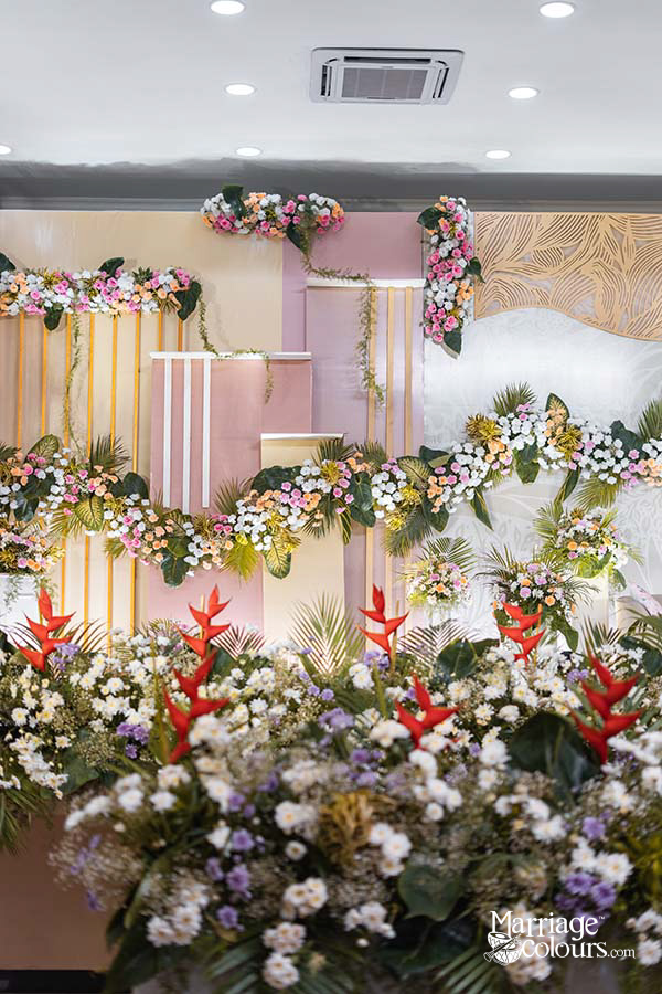 Wedding stage with floral garland, gold and pink backdrop, and textured wall design in a banquet hall