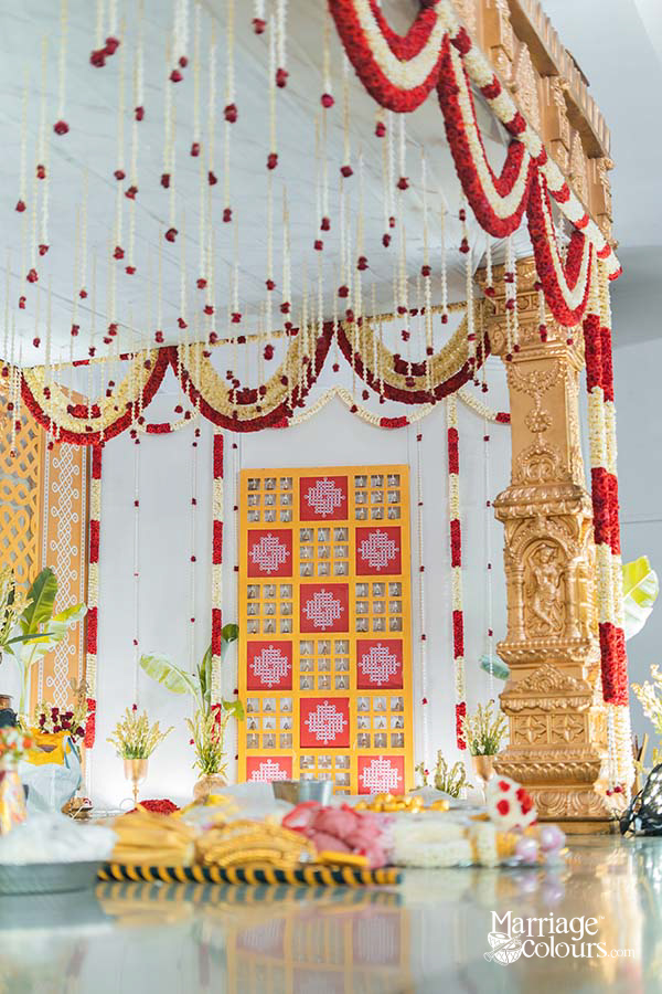 Decorative wall panel with red squares, white rangoli patterns, and hanging bells
