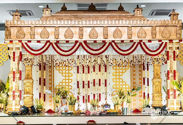 Ornate South Indian wedding mandap with gold and red floral decorations
