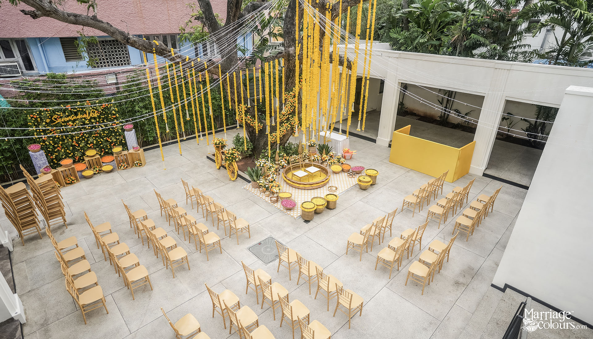 Haldi ceremony decor with hanging marigold strings, central tree setup, yellow theme seating and floral arrangements at Primrose venue