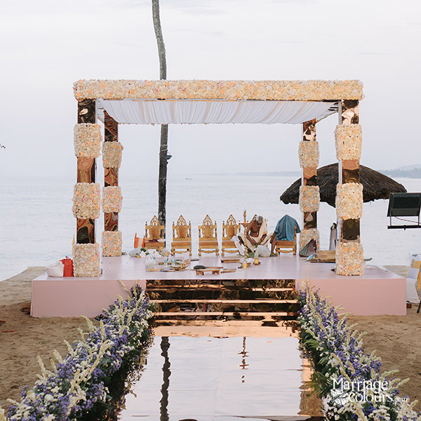 Beach wedding mandap with floral pillars and canopy setup facing the ocean