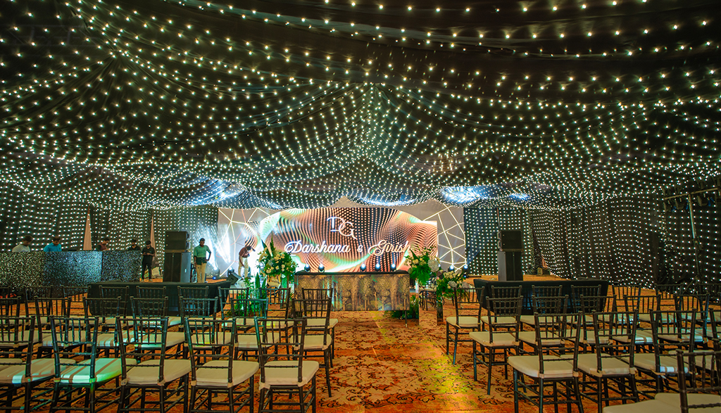 Luxury Indian wedding decor setup featuring floral stage design, elegant lighting, and themed decorations for Sangeet and Reception celebrations.