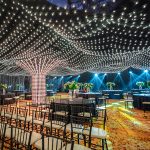 Luxury Indian wedding decor setup featuring floral stage design, elegant lighting, and themed decorations for Sangeet and Reception celebrations.